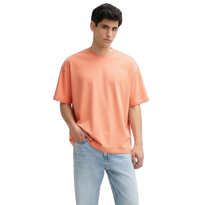 Man wearing a peach-colored t-shirt and light blue jeans on a white background